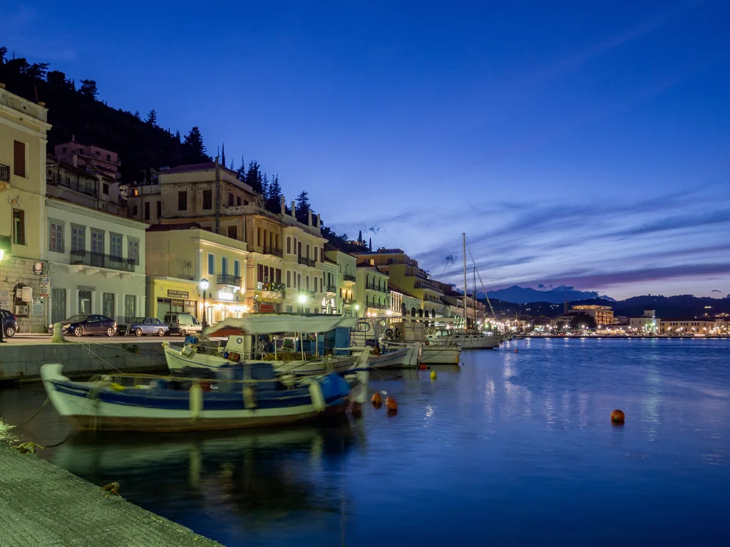 The Gythio quay at dusk, a wooden fishing boat moored in front