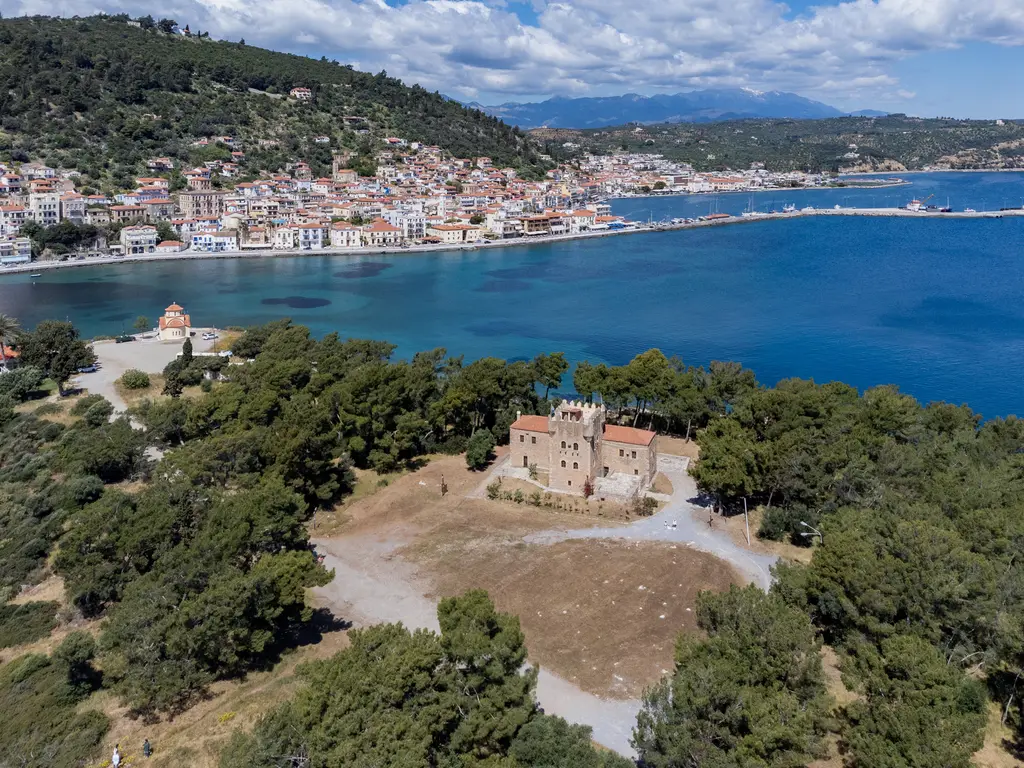 Kranai from above: the crenellated tower and a white chapel among the pines, Gythio across the water